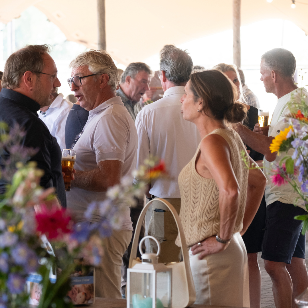 Personeelsfeest groep collega's pratend in tent met bloemen case