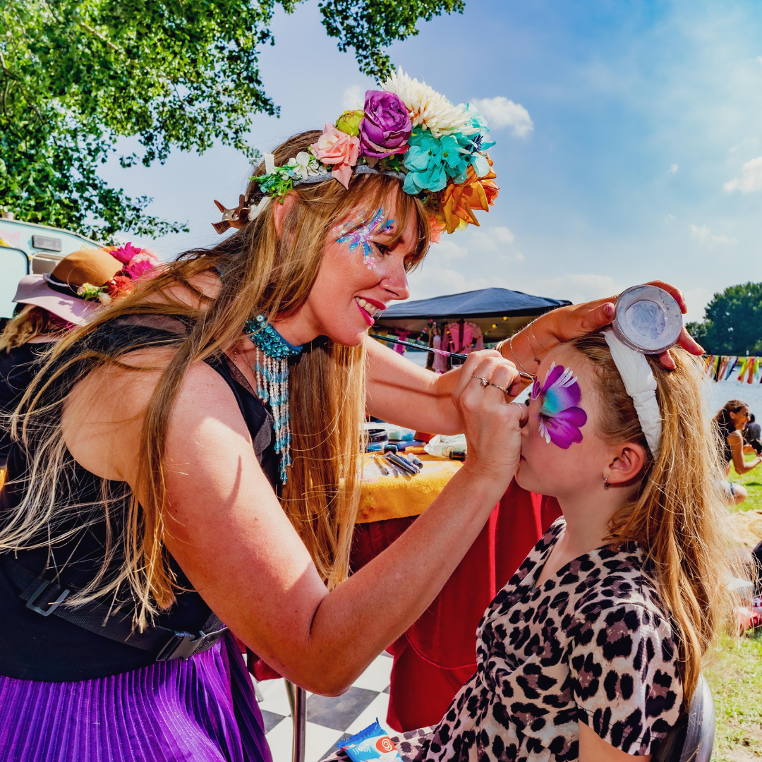 Strandfestival schminkende vrouw maakt kindje mooi