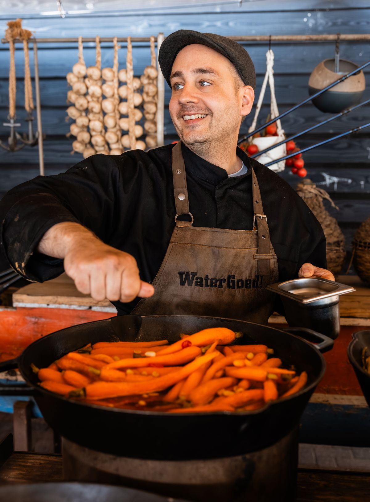 Lachende chef die de laatste hand legt aan een Thais wortelrecept
