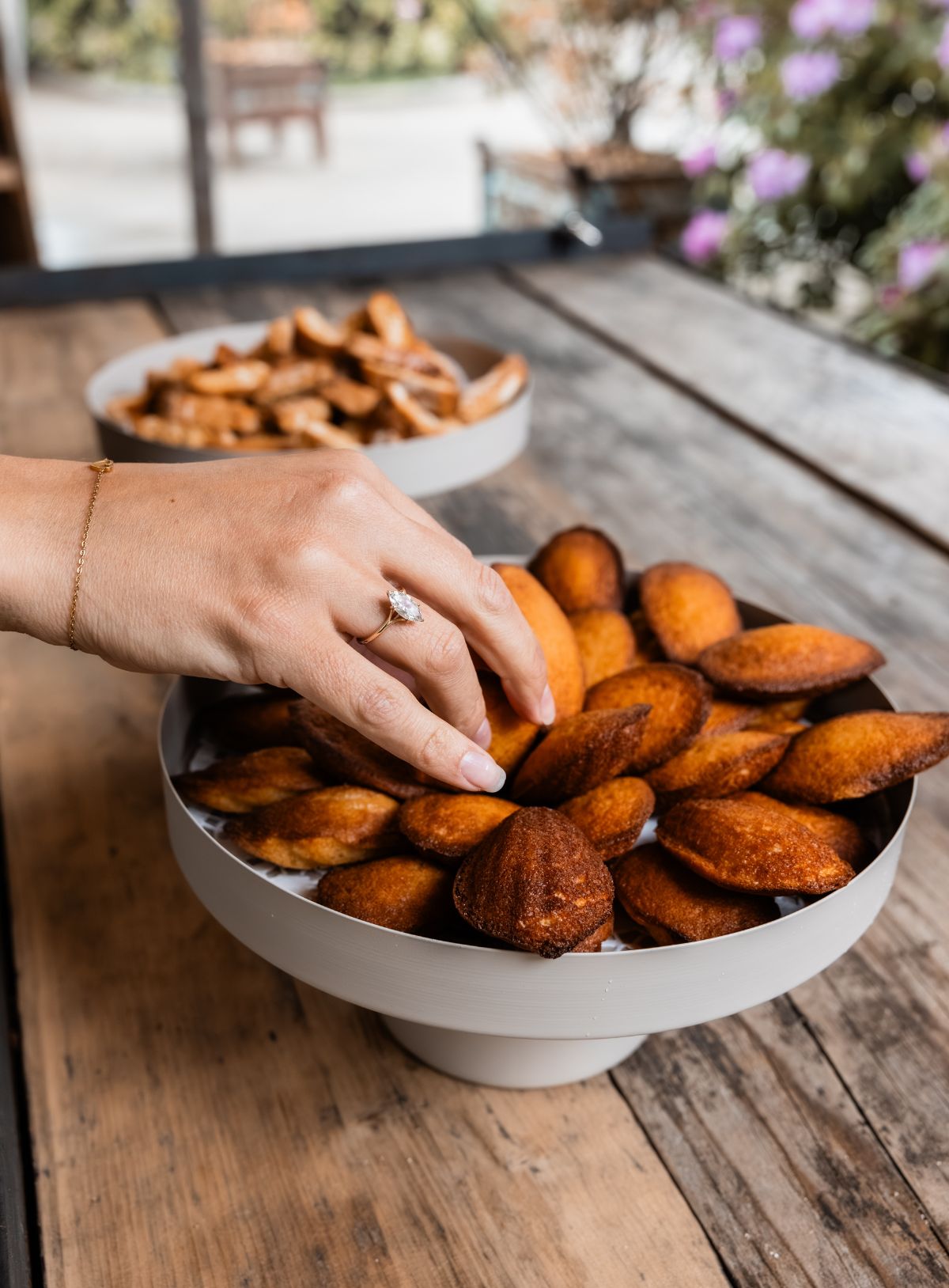 Hand die een madeleine uit een schaal pakt