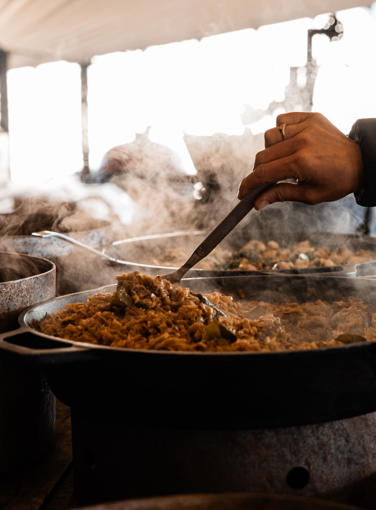 Een hand die in een pan met vegetarische rendang roert